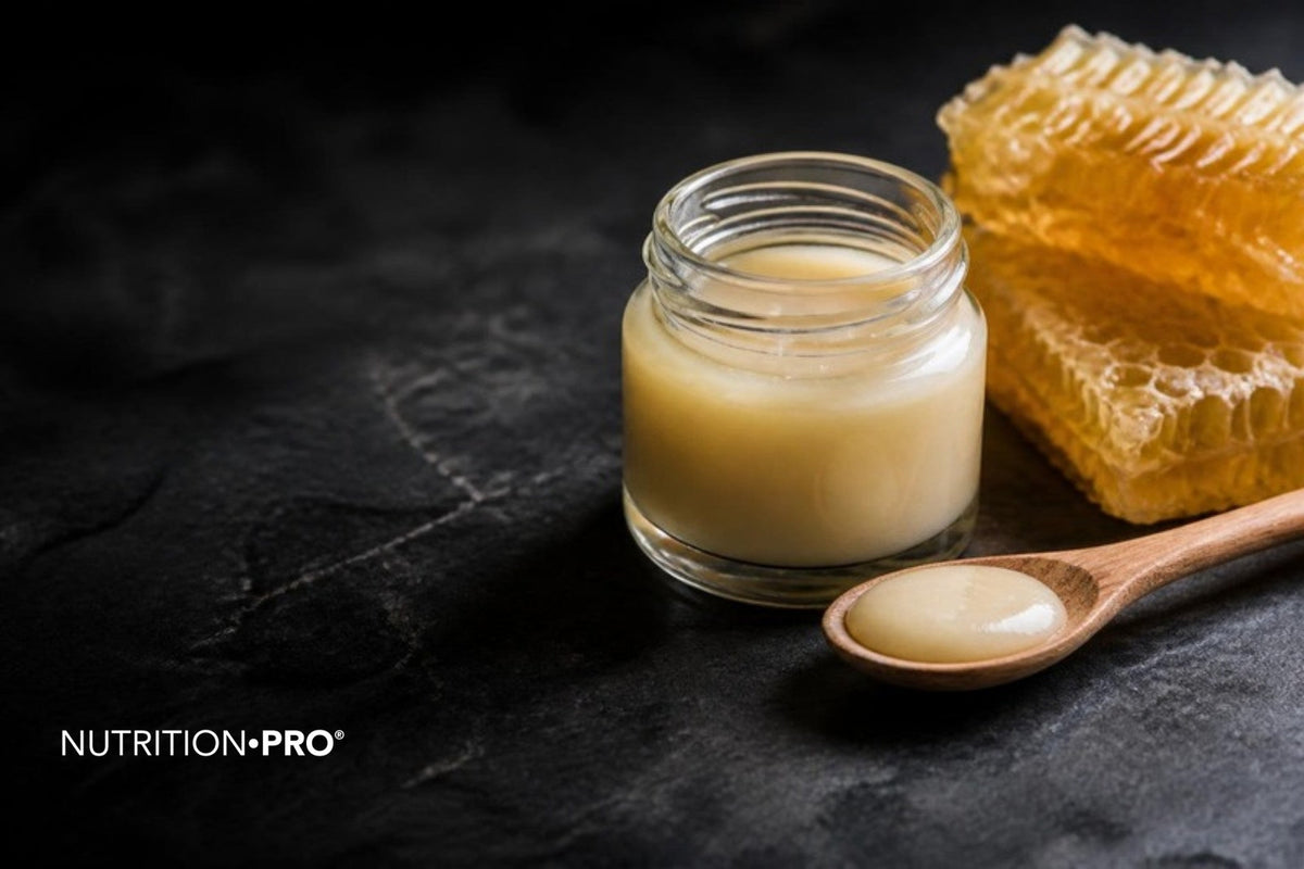 Pot de gelée royale crémeuse avec une cuillère et un rayon de miel sur une pierre sombre, gelée royale danger effets secondaires