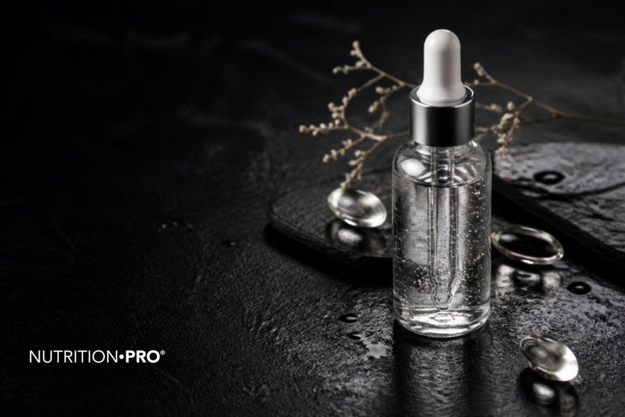 Flacon compte-gouttes de sérum transparent, gélules et gouttes d eau sur une pierre sombre, acide hyaluronique bienfaits et dangers