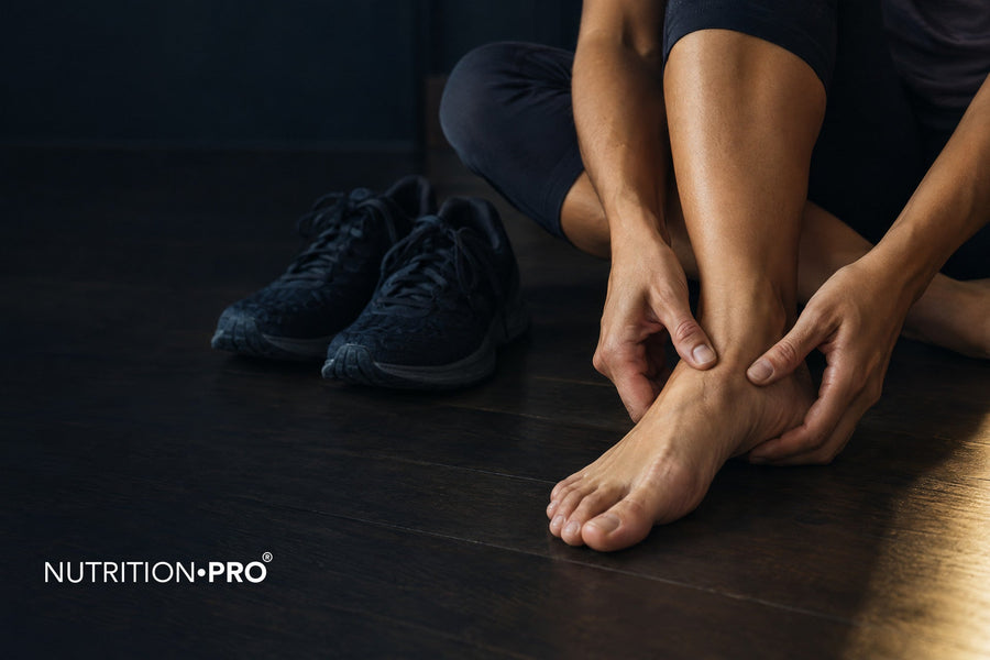 Coureuse qui se masse le pied nu à côté de ses chaussures de course, fasciite plantaire