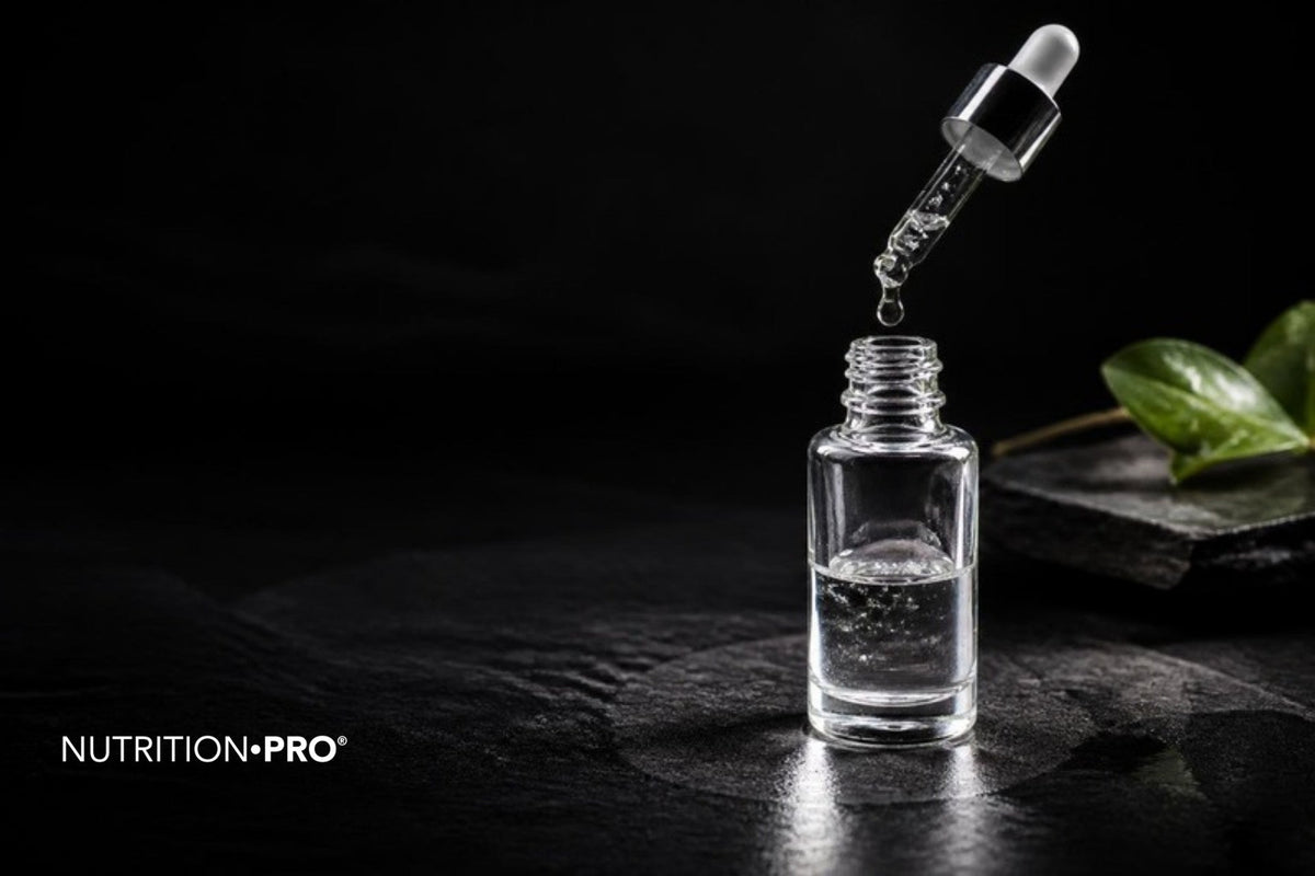 Flacon de sérum transparent et goutte de gel sur une ardoise sombre, sérum acide hyaluronique comment choisir et appliquer
